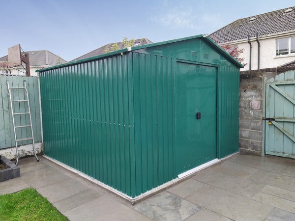 A green 10ft x 10ft steel garden shed in a garden in Dublin.