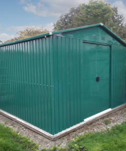 The 10ft x 10ft steel garden shed from Sheds Direct Ireland. It is a green, steel shed with vertical panels. The doors are closed, there is a metal frame around the edge at the bottom and there is grass in the foreground of the scene and blue skies above the shed