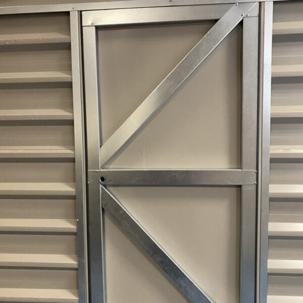 A heavy looking steel door with two 45 degree braced bars and a thick centre bar connecting them. Text at the bottom of the image reads 'new, heavier doors!'