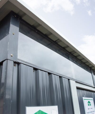 an external look at the full width window of the steel pent shed. The camera is at a low angle looking up at them and a blue sky is visible in the background.