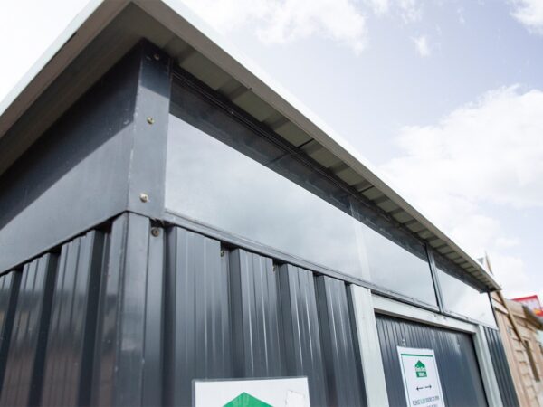 an external look at the full width window of the steel pent shed. The camera is at a low angle looking up at them and a blue sky is visible in the background.