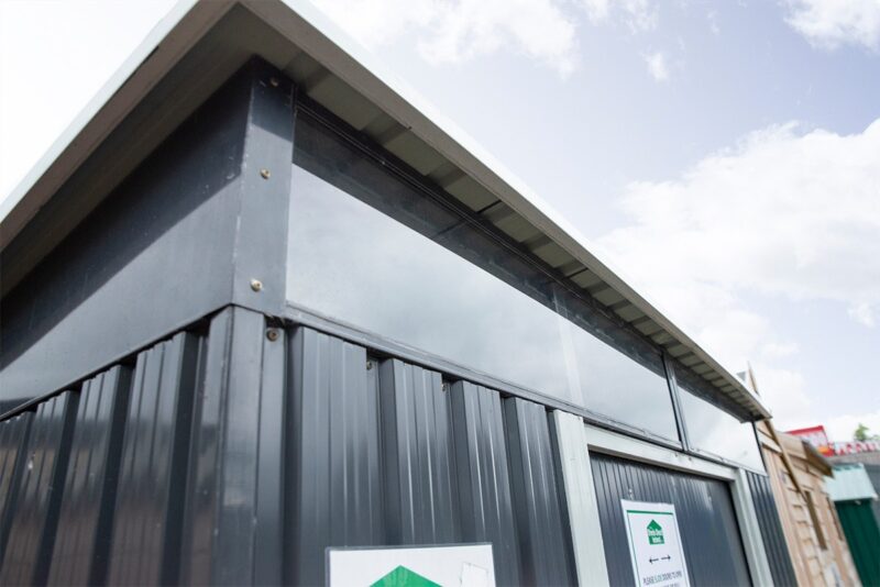 an external look at the full width window of the steel pent shed. The camera is at a low angle looking up at them and a blue sky is visible in the background.