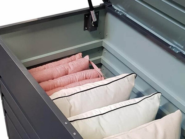 Inside the steel patio box. The box is open, the lid is visible and there are lots of cushions that are pink and white neatly lined up inside.