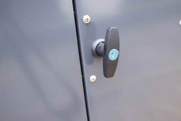 the bike store handle detail details from Sheds Direct ireland. There is a handle with a circular, blue lock visible in the middle of it. It's very clean and shiny.