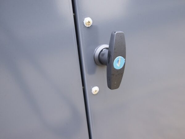 the bike store handle detail details from Sheds Direct ireland. There is a handle with a circular, blue lock visible in the middle of it. It's very clean and shiny.
