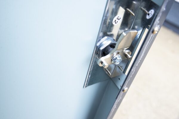 the bike store internal locking mechanism from Sheds Direct ireland. The walls are grey and the locking mechanism is a shiny steel. You can see a heavy hook in the front as the lock is in the 'open' position. It looks very safe.