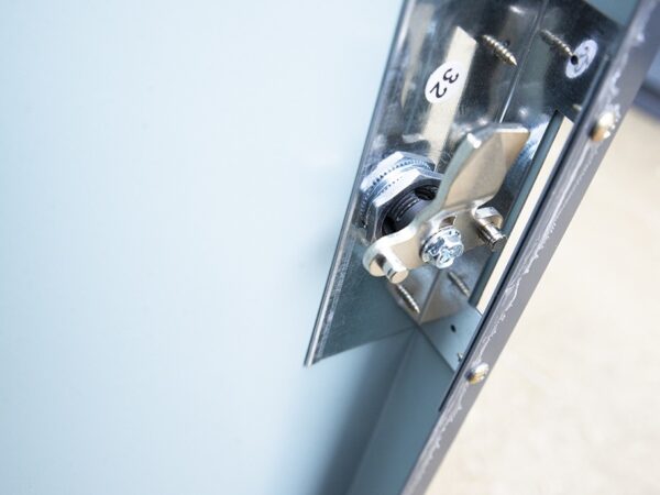 the bike store internal locking mechanism from Sheds Direct ireland. The walls are grey and the locking mechanism is a shiny steel. You can see a heavy hook in the front as the lock is in the 'open' position. It looks very safe.