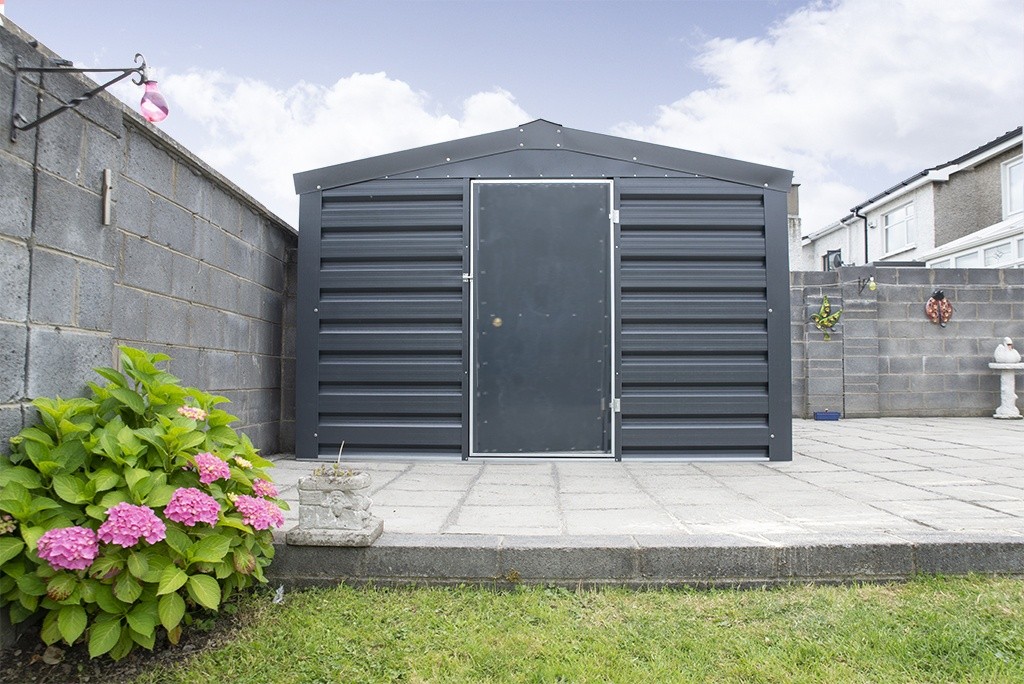 A heavy Duty, PVC Coated Shed in a Dublin garden. There is grass in the foregroiund and a pink flower to the left. The shed is sitting on