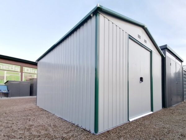 The Colossus Shed on the sheds direct ireland showroom as seen from a low angle. The doors and panels are white, the trim is green and above is a clear blue sky.