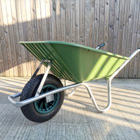 the 90l Wheelbarrow as seen from the front. It's at the front of the Sheds Direct Ireland showroom, against the wooden wall and the long shadows and yellow sun indicate it was taken on an early winter morning.