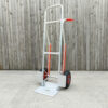 The aluminium hand truck with fold down footplate against a wooden wall