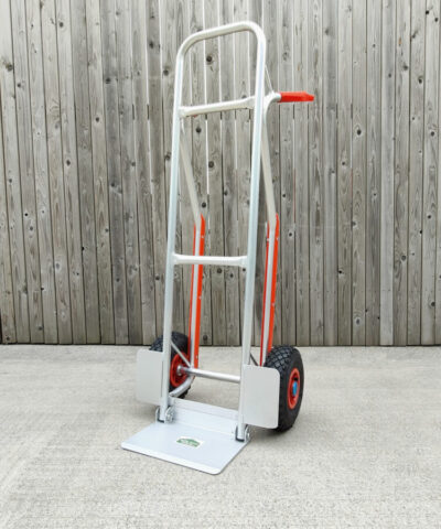 The aluminium hand truck with fold down footplate against a wooden wall