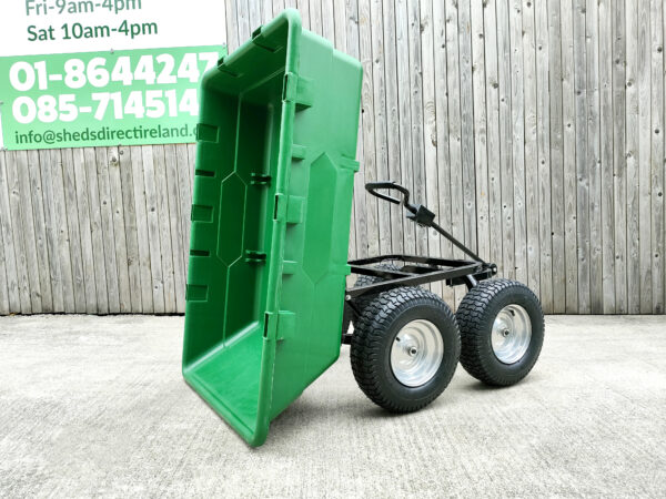 The 250L Tip Cart in the 'down' position against a wooden wall. It's bright green with a black chassis and black, pump tyres.