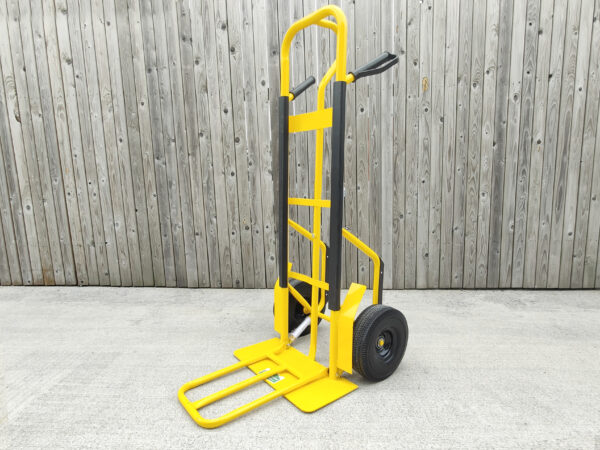 The Yellow Industrial Hand truck with extendable footplate against a wooden wall