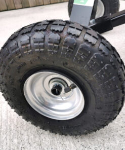 The picture is a close up of the large, black pneumatic tyres of the trailer dolly from sheds direct ireland. They have a steel, internal frame and a pump valvue is visible for inflating (if required)