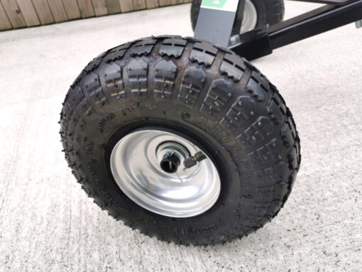 The picture is a close up of the large, black pneumatic tyres of the trailer dolly from sheds direct ireland. They have a steel, internal frame and a pump valvue is visible for inflating (if required)