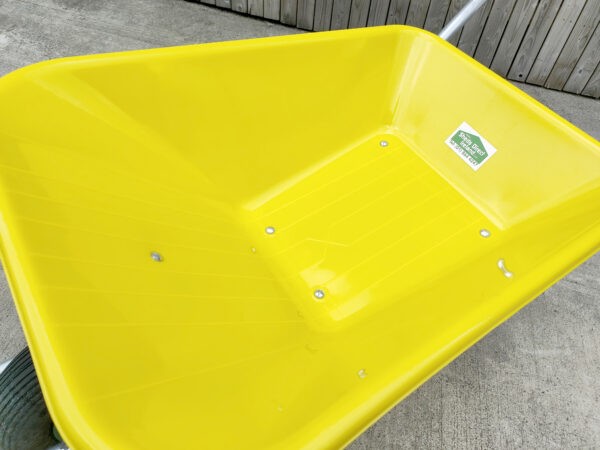 A detailed view of the bucket on the yellow wheelbarrow