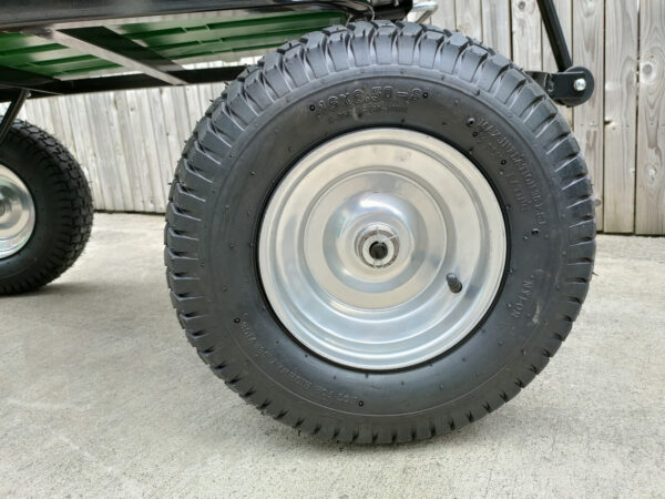The 250L tip cart tyres as seen up close in a side profile. The centre is a reflective silver colour and the outside has deep black grooves in the tyre.