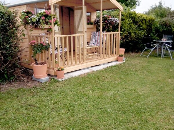 a side view of a wooden chalet with veranda