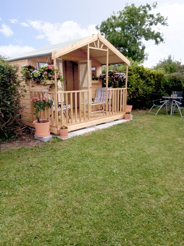 a side view of a wooden chalet with veranda
