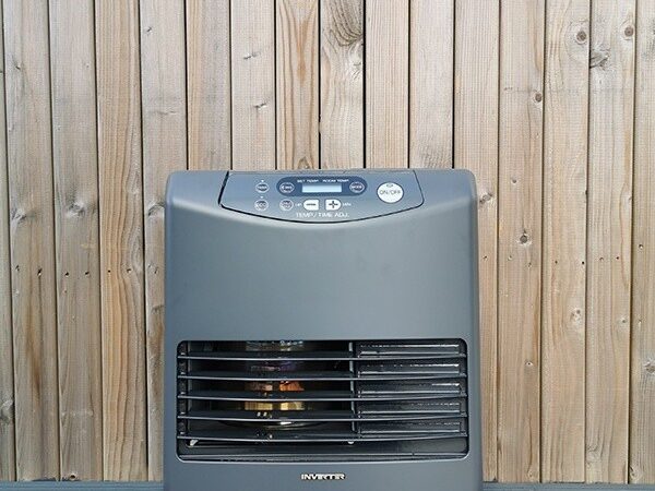The Inverter 5086 Heater against a wooden backdrop wall. It's at eye level and you can see the heating mechanism through the grate inside.