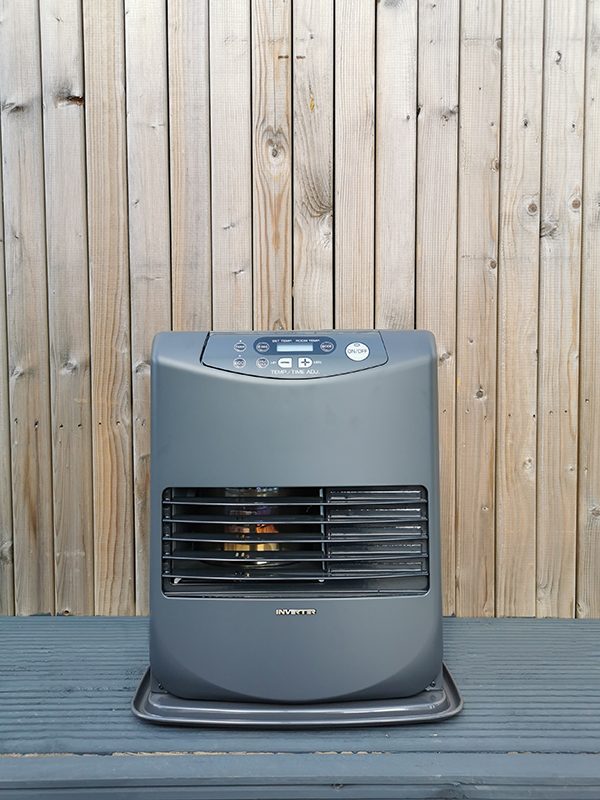 The Inverter 5086 Heater against a wooden backdrop wall. It's at eye level and you can see the heating mechanism through the grate inside.