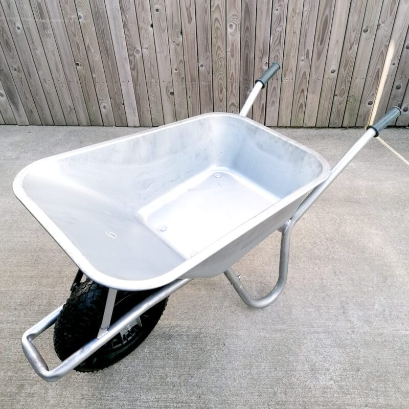 A steel wheelbarrow as seen from a high angle. The inside is bright and semi-shiny.