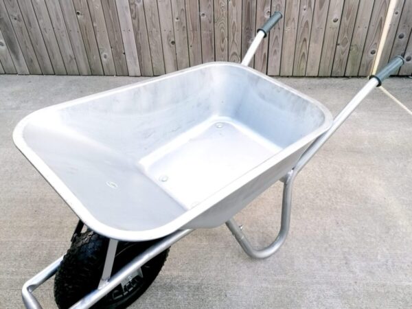 A steel wheelbarrow as seen from a high angle. The inside is bright and semi-shiny.