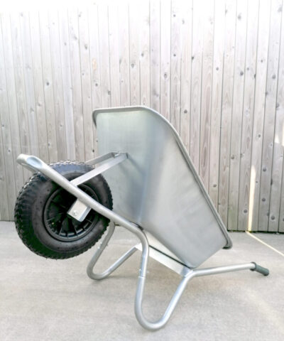 The steel wheelbarrow is lying on its back, the handles and support bars are on the ground and the wheel is raised. It takes up less floor space like this.