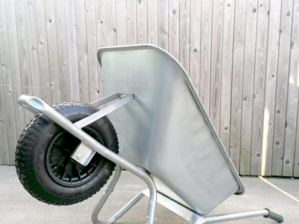 The steel wheelbarrow is lying on its back, the handles and support bars are on the ground and the wheel is raised. It takes up less floor space like this.