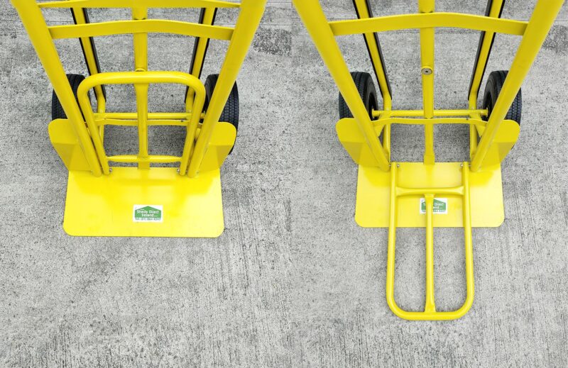 Two industrial hand truck plates side by side, one with the plate up, the other has it down