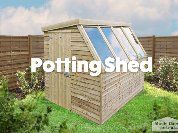 The Sheds Direct Ireland potting shed in a garden in Skerries. It's on the left hand side of the frame and there is a green lawn under it, which runs into the forground. To the right there is a plastic greenhouse and two thin trees about 7 ft tall are either side of the shed. The shed is a golden-brown colour and three large glass panels are on the right hand side of the shed at an approximate 15 degree angle, sloping down.