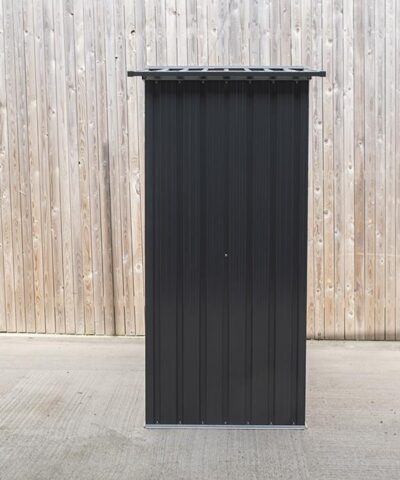 The side view of the small shed. It is about twice as tall as it is wide. It's grey-black and the roof overlaps the body of the shed by about 3 inches either side