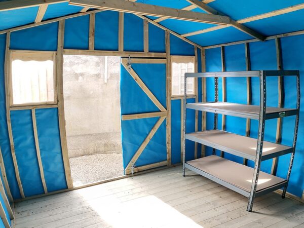 A vertical image taken inside the taller wooden shed. The sides are warped, as a fish-eye lens has been used. The walls inside the shed are blue, the floor is a pale wood colour and light is pouring in the door. Outside the door, only a grey wall is visible