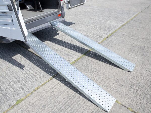 Car Ramps made of Galvanised Steel attached to the back of a Bus. The bus has the doors open and the steel ramps are reflecting the sun into the camera. The ramps support 1500kg.