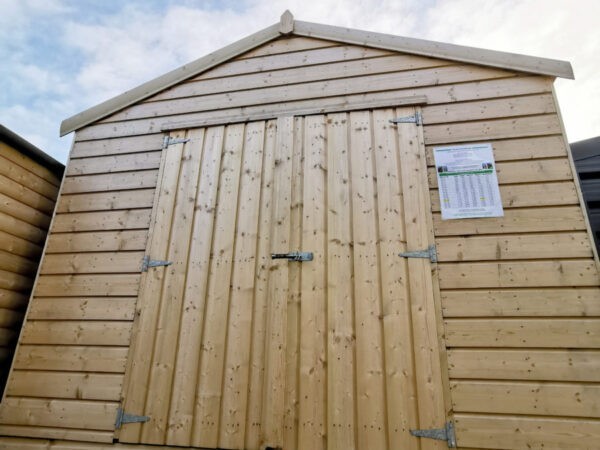 a Taller Wooden Shed as seen from a low angle. It's golden-brown, with horizontal wooden planks on the body and vertical planks on the door. There is a bolt lock and 3 hinges on each door. The sky is bright blue with dotted, but sweeping clouds above.