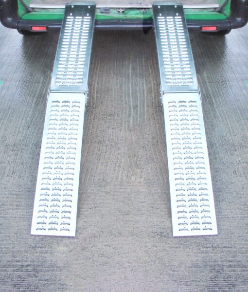 Two Folding Ramps lined up and raised to the back of a green van. The ground below is slick and wet looking and it reflects