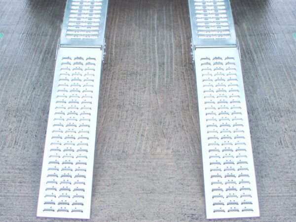 Two Folding Ramps lined up and raised to the back of a green van. The ground below is slick and wet looking and it reflects
