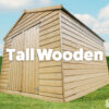 tall wooden shed on grass with blue sky and green hedges.