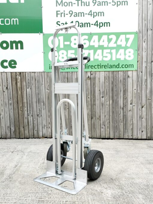 The three in one hand truck from sheds direct ireland against a wooden wall which has the stores phone numbers on them