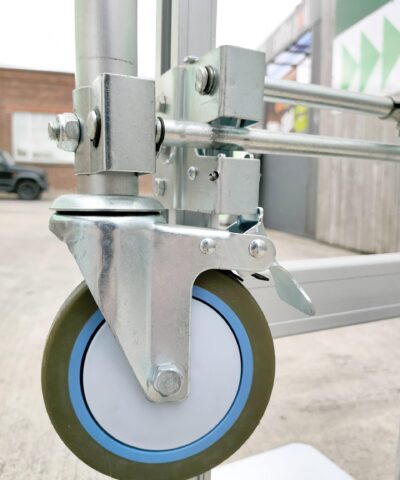 The dolly wheel in position on the back of the 2 in 1 hand truck. The wheel is small, rubber and lined with a blue plastic ring.