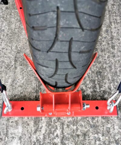 A top down view of the stand, showing the wheel in the back port. There are black and red cable straps holding the wheel securely in position. There are deep traction grooves on the wheel.