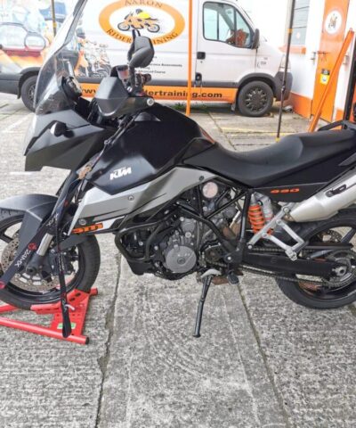 A side view of the motorbike on the stand. There are straps holding the bike in place and the bike stand is suspender, i.e. it is not touching the ground