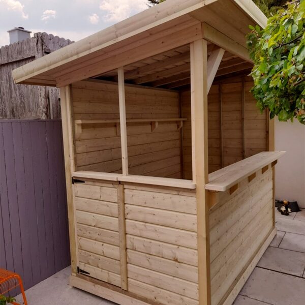 The side aspect of the wooden garden bar where the door is. The roof is clearly sloping from front to back