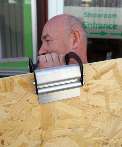 A man carrying a large sheet of ply with the panel carrier