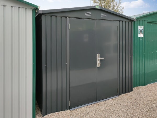A view of the premium apex shed as seen from the sheds direct ireland showroom. It's a dark grey and it's sitting between a white-grey shed to the left and a dark green one to the right