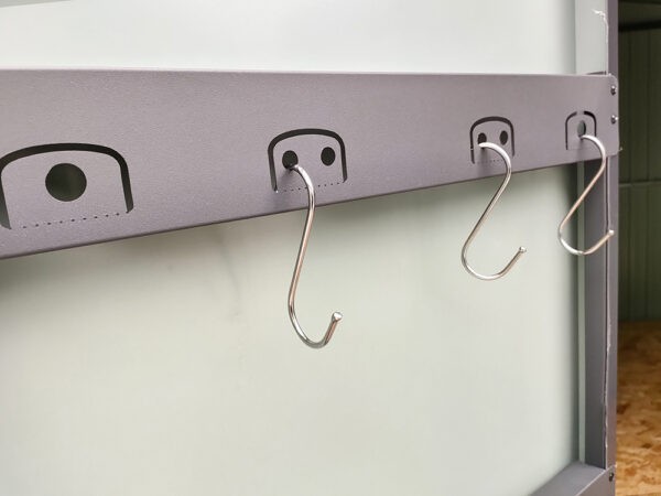 The built in tool hooks on the premium sheds. They are rounded rectangles with one end attached to the door. They have one or two large circular holes in the centre which can support tools. In the image 'S-hooks' are in position.
