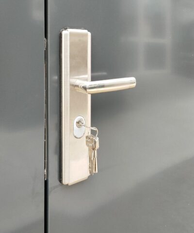 The built in handle lock of the premium shed. It is a pale silver with a long, protruding handle above the keyhole. The walls of the shed are an anthracite grey colour