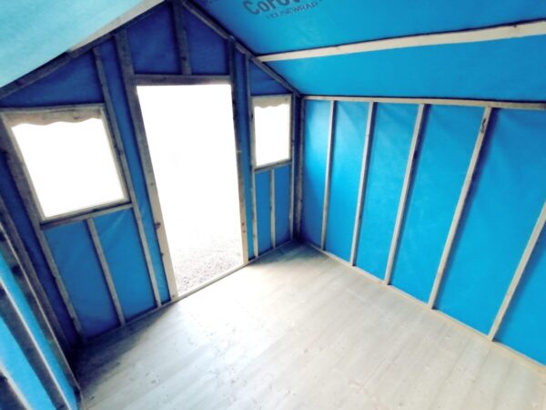 The blue interior of the overhang shed. The outside is bright and light spills into this shed from a low angle