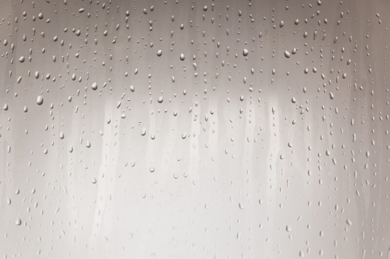 Condensation forming and water droplets running down a pane of glass